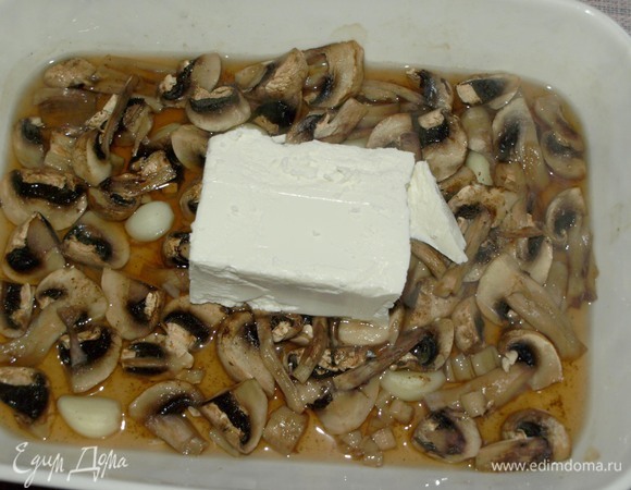 Достаем грибы из духовки, сверху добавляем фету (целым куском) и отправляем назад в духовку на 10 минут.