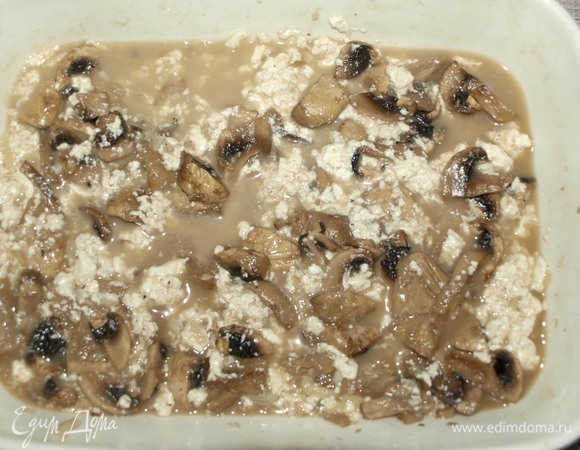 Достаем грибы с фетой из духовки. Разминаем вилкой чеснок и фету.