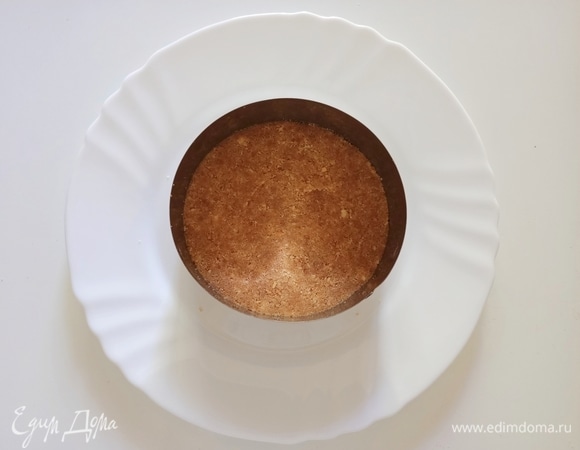 Печенье измельчить до состояния крошки и смешать с растопленным сливочным маслом. На блюдо поставить металлическое кольцо диаметром 12 см, на дно выложить печенье, утрамбовать и поставить в холодильник на 15–20 минут.