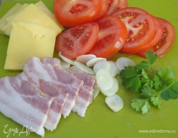 Бекон, помидоры, сыр и луковицу нарезать пластинками, зелень освободить от веточек, оставить только листочки. Отделить желток от белка и смешать его со столовой ложкой молока.