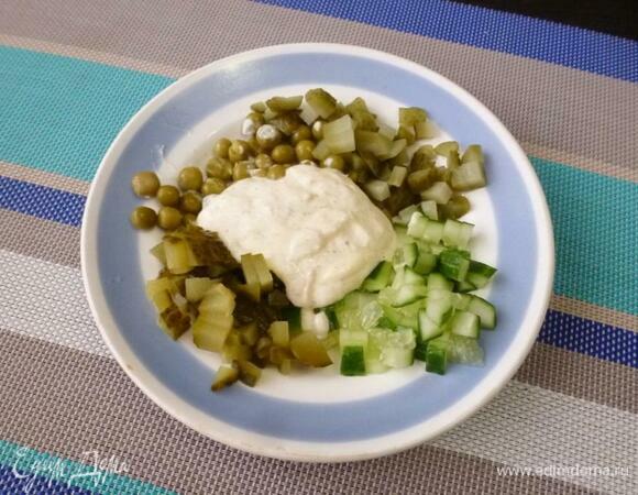 Нарезать огурцы мелкими кубиками, добавить зеленый горошек. Горошек лучше примять вилкой. Смешать майонез со столовым хреном и заправить овощную нарезку с горошком.