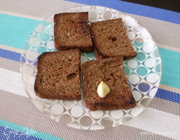 Натереть зубчиком чеснока подсушенную сторону хлеба.