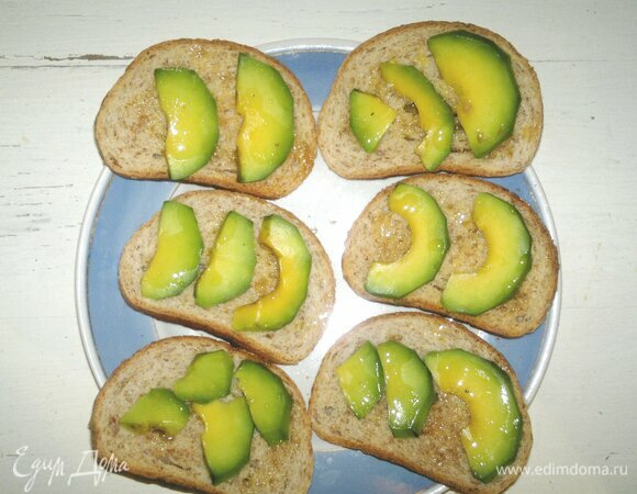 На хлеб выложить ломтики авокадо, полить льняным маслом.