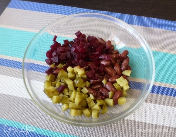 Сварить фасоль, ориентируясь на рекомендации производителя. Нарезать кубиками соленые огурцы и вареную свеклу. Переложить в миску к фасоли.