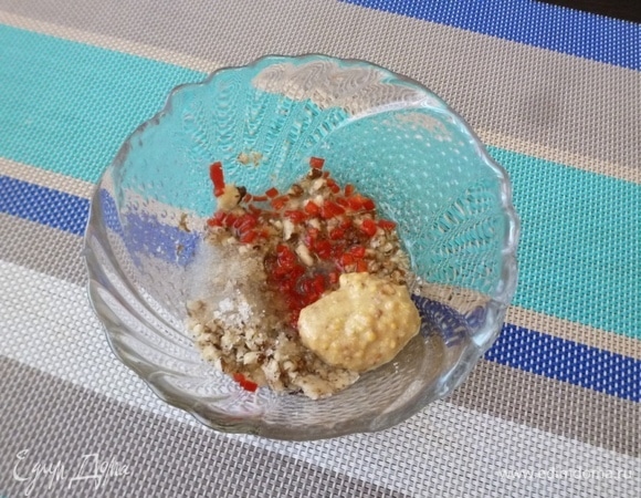 Приготовить заправку для салата. Грецкие орехи размять пестиком. Влить в миску растительное масло, положить горчицу и измельченный перец чили. Немного посолить (но помните, что в салате будут соленые огурцы).