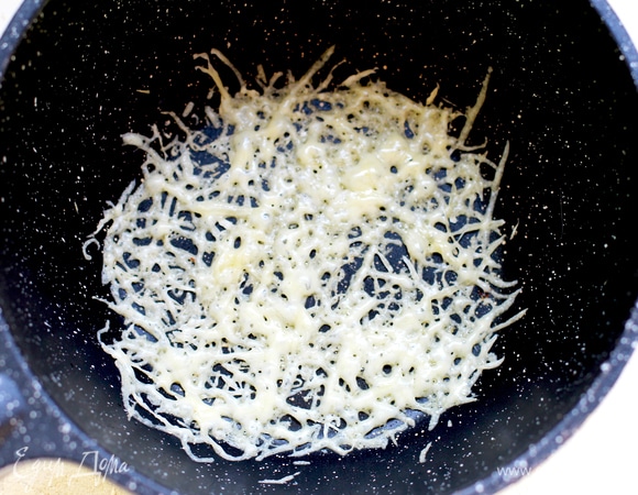 На разогретую сковородку (без масла!) выкладываем тонким слоем сыр. Держим на плите, пока сыр не расплавится и слегка не подрумянится. Снимаем сырный чипс на доску или тарелку, ждем остывания.