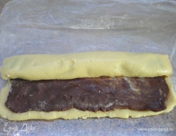 Раскатайте оба вида теста между двумя листами пергамента, слегка припудренного мукой, в прямоугольники. Белый прямоугольник должен быть немного длиннее шоколадного. Наложите шоколадный пласт на белый, заверните в рулет, затем в пленку и уберите в холодильник на 3 часа.