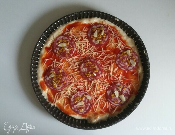 Начинаем выкладывать начинку. Достаем из холодильника сырокопченую колбасу с горчицей и чесноком и выкладываем поверх сырного слоя.