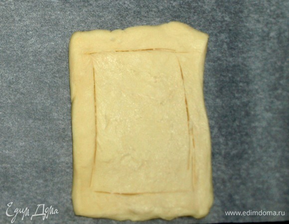 Слоеное тесто разморозить. Разделить на четыре равные части. Каждую часть немного раскатываем или растягиваем руками. Выкладываем тесто на противень, застеленный пекарской бумагой. Аккуратно намечаем ножом границы, отступив 0,5 см от края.