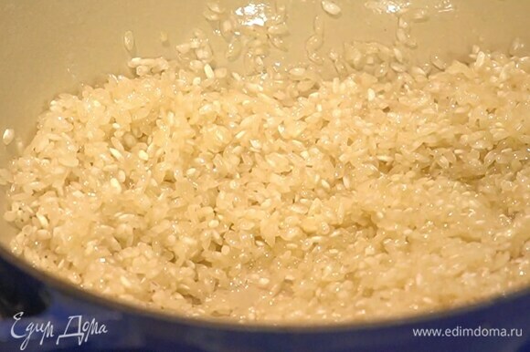 Разогреть в сковороде оливковое и сливочное масло и слегка обжарить рис, затем добавить лук и, помешивая, готовить, пока он не станет прозрачным.