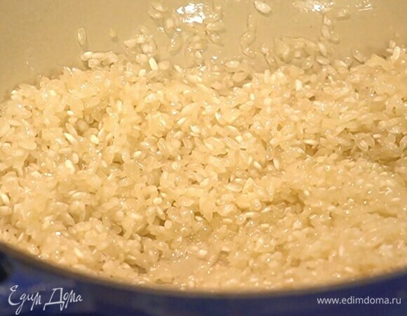Разогреть в сковороде оливковое и сливочное масло и слегка обжарить рис, затем добавить лук и, помешивая, готовить, пока он не станет прозрачным.