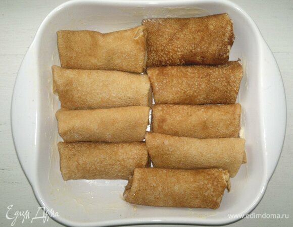 Форму для запекания смазать сливочным маслом, выложить нафаршированные блинчики.