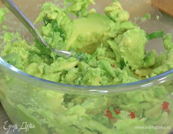 Приготовить гуакамоле: из авокадо ложкой вынуть мякоть и перемешать с измельченным чили, затем добавить половину нарубленной кинзы и еще раз перемешать.