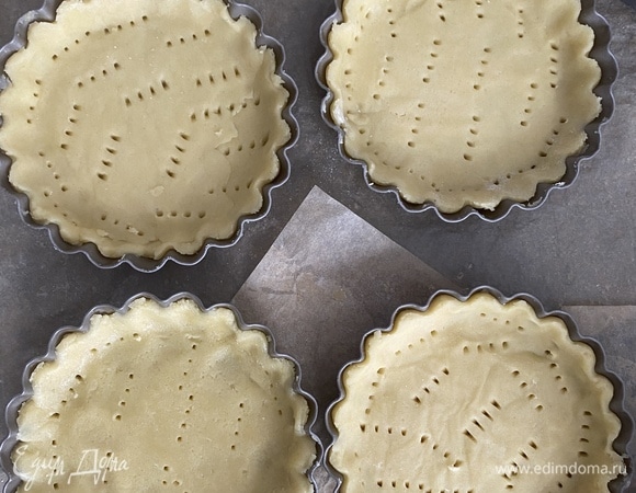Охлажденное тесто разделить на 4 части, выложить тесто в формочки, прижать, наколоть вилкой по всей поверхности.