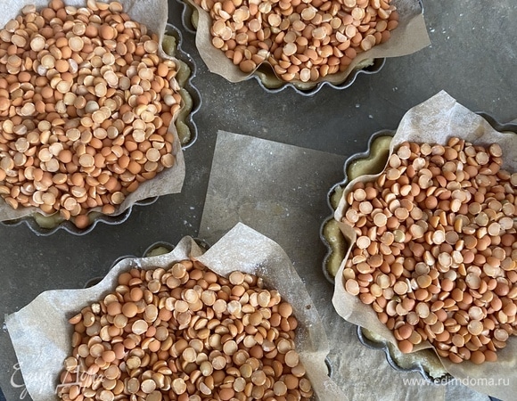 Сверху положить листы пергамента , на который насыпать бобовые, получится груз, который не даст тесту подниматься. Выпекать в заранее разогретой до 180°C духовке 15–20 мин.