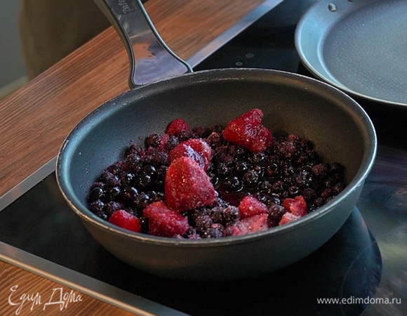 В отдельную сковороду выложите замороженные ягоды, добавьте сахар и воду. Уваривайте до загустения на среднем огне.