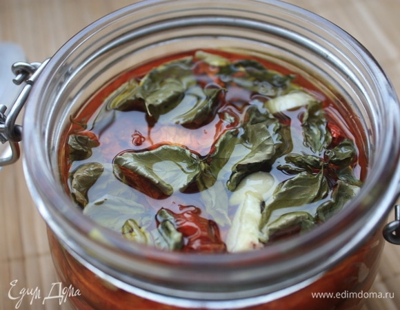 Готовые помидоры выложите в стерилизованную емкость, добавьте нарезанные дольки чеснока и залейте горячим оливковым маслом, чтобы оно полностью их покрывало. Я также добавляю подсушенный базилик. Закройте банку с вялеными томатами и оставьте минимум на 5–6 часов.