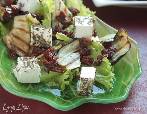 Выложите листья салата, на них распределите баклажаны, вяленые томаты и сыр, сбрызните салат заправкой и наслаждайтесь!