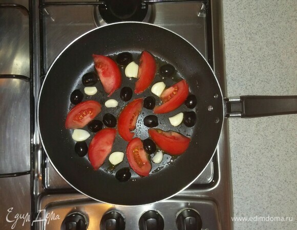 Смазываем сковороду маслом, выкладываем на нее овощи (половинки долек чеснока и маслины кладем стороной среза вниз) и ставим на мелкую конфорку плиты на средний огонь. Нужно обжарить овощи по 3–4 минуты с каждой стороны.