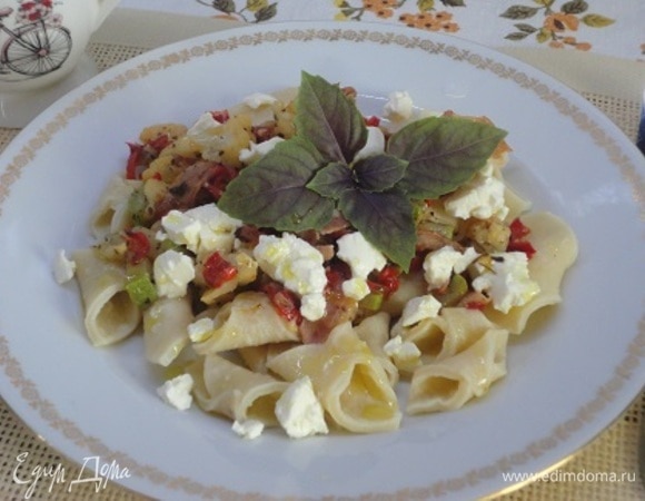 На тарелку выложить гаргарелли, сверху — овощи и кусочки рассольного сыра. Подавать со свежим базиликом.