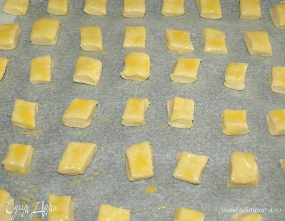 Выладываем печенье на противень, застеленный пекарской бумагой. Смешать желток с молоком и смазать печенье.