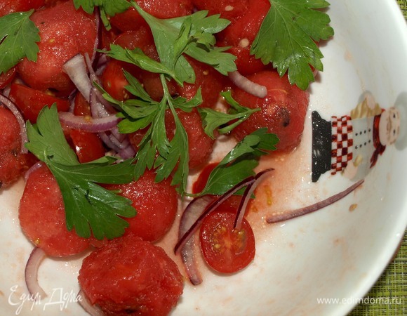 К арбузу добавить разрезанные на две части помидоры черри, петрушку, нарезанный перьями лук. В миске смешать яблочный уксус с сахаром, добавить растительное масло и заправить салат. Перекладываем в салатницу.