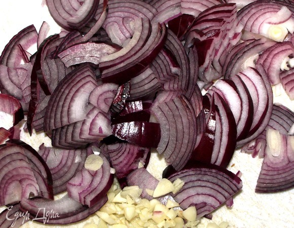 Лук очистить, разрезать на четыре части и нарезать перьями. Чеснок очистить и мелко порубить.