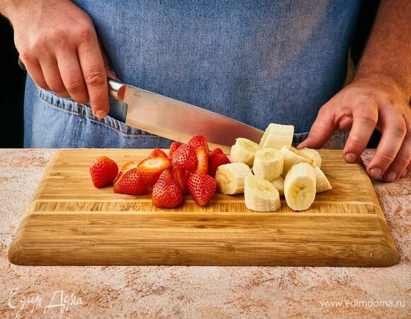 Банан почистите и крупно нарежьте. С клубники удалите листочки. Выложите в блендер.