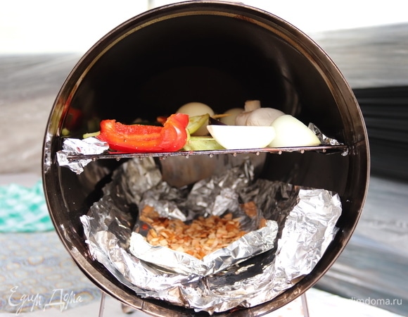 Коптилка у нас бочонком. Дно застелили фольгой для удобства. Щепу для копчения (у нас вишня) замочить в воде на 30–40 минут. На решетке разложить кусочки овощей в один слой. Поставить коптилку на «седые» угли и, когда из под крышки появится легкий дымок, коптить минут 15–25. Время зависит от желаемой степени копчения. Но дольше коптить не советую — овощи могут горчить.