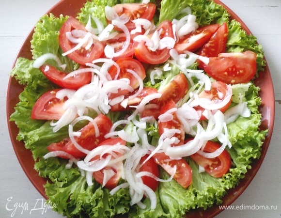На листья салата выложить дольки помидоров. С лука слить жидкость и выложить лук на помидоры.