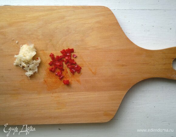 Чеснок очистить, пропустить через пресс. Из перца чили удалить семена. Часть перца нарезать мелкими кубиками, остальное — тонкими колечками.