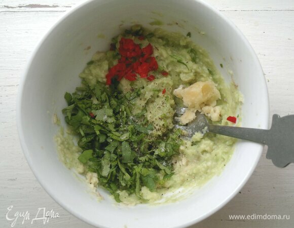 В миску с авокадо положить нарезанную кинзу, кубики чили, чеснок, немного посолить и поперчить, перемешать. 