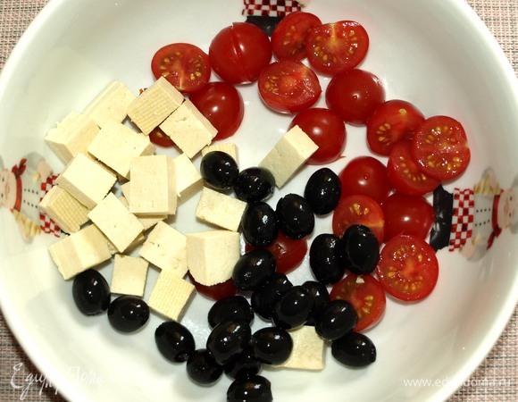 Все овощи хорошо промыть. В миску добавить помидоры черри, нарезанные половинками, тофу, нарезанный кубиками, маслины.