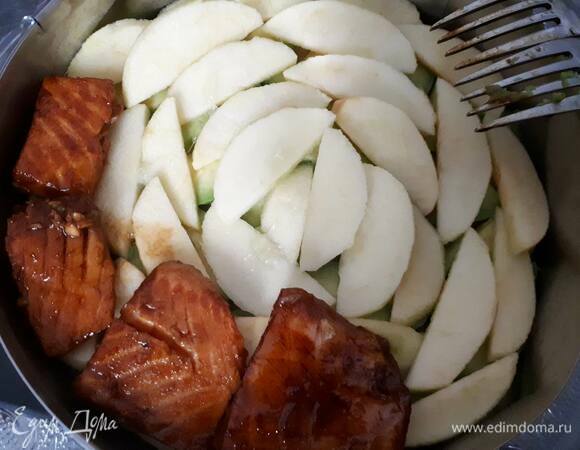 Выложите лосося на слой яблок. Толстые кусочки можно разрезать вдоль на две части.