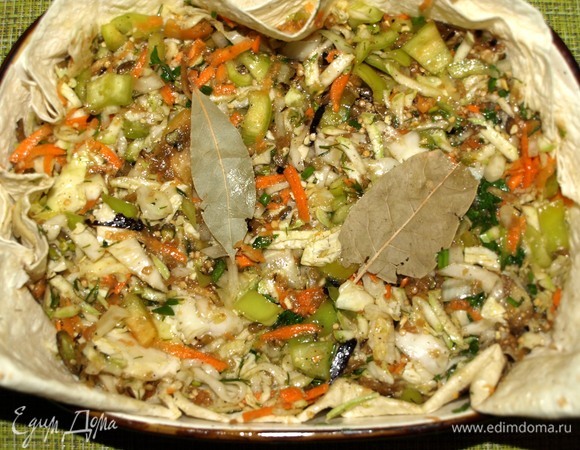 Овощи складываем в миску, добавляем растительное масло и приправы. Все хорошо перемешиваем. Приправы и специи лучше регулировать по своему вкусу. Тонкий лаваш складываем вдвое, кладем в форму для запекания, чтобы получились бортики. Этот процесс можно пропустить, но лаваш впитает весь лишний сок, края подпекутся, и это будет очень вкусно. Перекладываем в форму овощи, разравниваем. Добавляем лавровый лист.