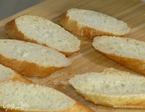 Багет нарезать кусочками и смазать с одной стороны сливочным маслом.