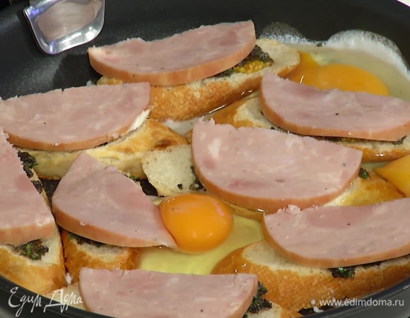 Ветчину нарезать тонкими ломтиками, выложить сверху на хлеб, разбить в сковороду яйца, посолить и поперчить, накрыть крышкой и жарить до готовности яиц.