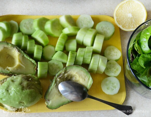Авокадо отделите от кожуры, нарежьте мякоть (получилось 300 г). Огурцы также вымойте, снимите шкурку и нарежьте дольками (получилось 350 г). Зелень вымойте и обсушите.