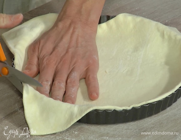 Рабочую поверхность присыпать мукой, немного раскатать тесто и выложить в форму для тарта, лишние края срезать. Накрыть бумагой для выпечки, засыпать любыми бобовыми и выпекать в разогретой духовке 15 минут до полуготовности.