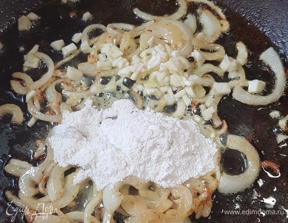 Чеснок мелко порубить и добавить к луку. Обжарить 1 минуту. Всыпать муку. Все тщательно перемешать.