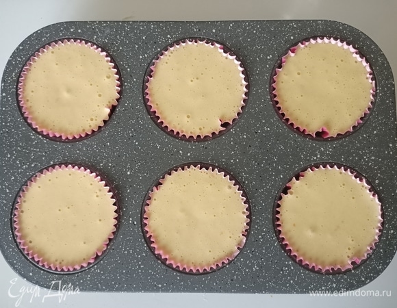 В форму для маффинов вставить бумажные формочки и заполнить их тестом.