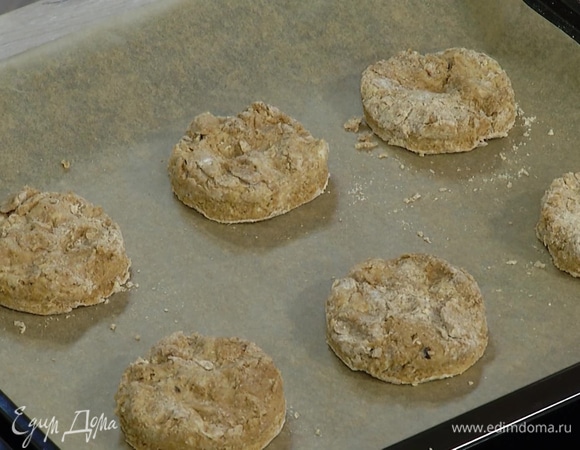 Присыпать рабочую поверхность мукой, выложить тесто и сделать из него пласт высотой 1,5–2 см, затем кулинарным кольцом вырезать из теста кружки и выложить на застеленный бумагой для выпечки противень.