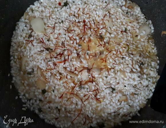Всыпьте рис и обжаривайте в течение 1–2 минут. Затем влейте вино и оставьте выпариваться. Всыпьте шафран и влейте половник бульона. Готовьте на медленном огне, вливая бульон по одному половнику каждый раз, как жидкость выпарится. Перемешивайте время от времени.
