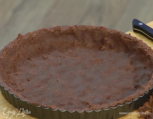 Две трети теста раскатать в пласт и выложить в форму для тарта, накрыть пекарской бумагой, засыпать любыми бобовыми и выпекать в разогретой духовке 15 минут до полуготовности.