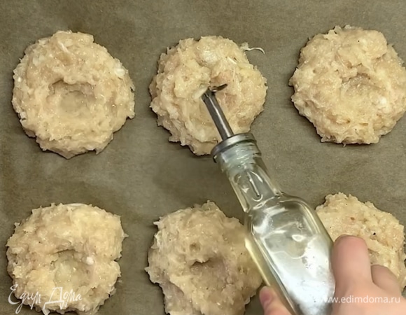 Выкладываем на противень, застеленный бумагой для выпекания, 6 шариков. В серединке делаем углубление ложкой и наливаем немного масла.