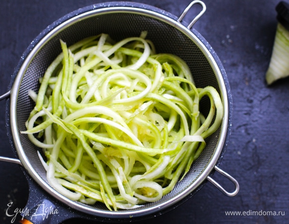 Удалить влагу из кабачков. Для этого натертые с помощью точилки с крупным диаметром (у меня толщина удона) кабачки посолить и положить в дуршлаг на 20–30 минут. Затем отжать и переложить на бумажные полотенца.