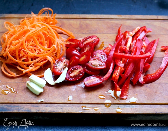 Морковь натереть на корейской терке или тоже использовать точилку, только диаметром меньше (у меня толщина «спагетти»). Перец нарезать полосками, черри — пополам, чеснок — крупно. В сковороде на смеси оливкового и кунжутного масел обжарить чеснок до румяности (не до черноты, масло будет горчить). Достать чеснок, мы его используем только для ароматизации масла. Далее в этом масле слегка обжарить морковь, добавить перец, готовить до мягкости, положить черри. Все вместе жарить 1–2 минуты.