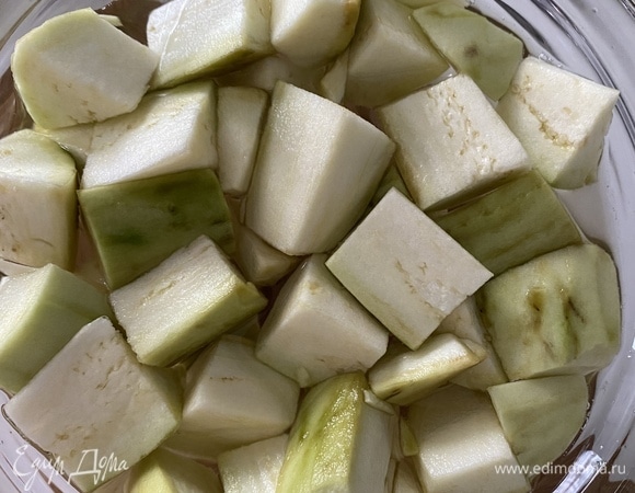 Баклажан очистить, крупно нарезать кубиками, хорошо посолить. Залить холодной водой, перемешать, отставить на 30 минут. Спустя время воду слить, баклажаны промыть и выложить на бумажные полотенца. Хорошо просушить от влаги.