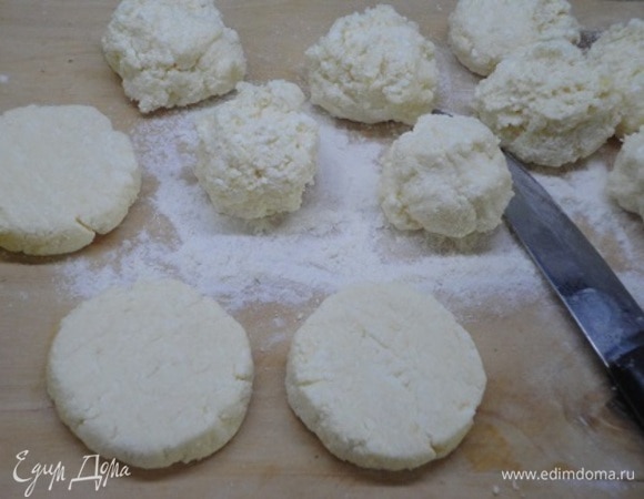 Получившуюся массу разделить на 11–12 кусочков примерно по 60–65 г. Я для этого использую весы. Так изделия получаются одинаковыми. На доске, припыленной мукой, с помощью ножа формируем сырники.