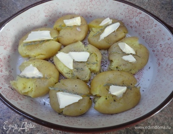 Дно формы для запекания смазать растительным маслом. Зубчики чеснока раздавить ножом и выложить на дно формы. Я, из-за недостаточного количества чеснока, порубила его. Картофель слегка раздавить ложкой, чтобы лопнула кожура. Сверху посыпать перцем, выложить веточки тимьяна, а на каждую картофелину — по кусочку сливочного масла.